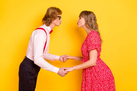 Photo portrait of cheerful lovely couple kissing on date valentines day isolated on vibrant yellow...