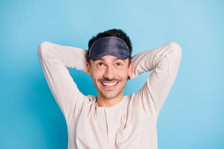 Portrait of nice cheerful brunet guy wearing eye mask resting looking up isolated over bright blue...