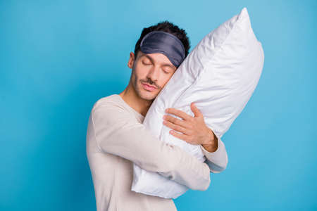 Portrait of nice peaceful guy enjoying embracing lying on soft pillow harmony isolated over bright...