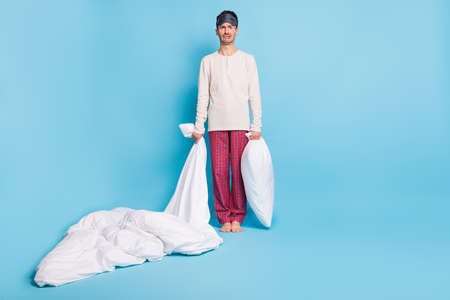 Photo portrait full body view of unhappy sad man holding blanket pillow in hands isolated on vivid blue colored backgroundの写真素材