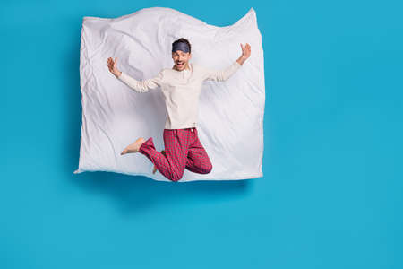 Full length photo portrait of excited guy jumping up with blanket behind isolated on vivid blue colored backgroundの写真素材