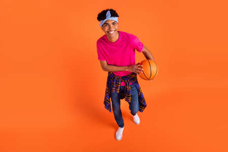 Top above high angle view of afro american happy man hold basketball wear tight shirt isolated on orange color backgroundの写真素材