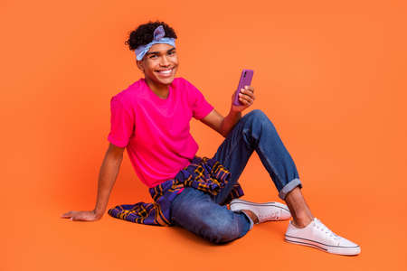 Full length body size photo of happy young man sitting using cellphone app browsing internet...