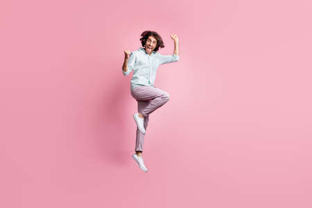 Full length photo of excited smile young man happy win victory goal fists hands jump isolated over pink color backgroundの写真素材