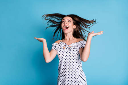 Photo of young excited girl open mouth look empty space wear dotted dress isolated blue color backgroundの写真素材