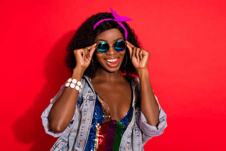 Photo of adorable funky curly dark skin woman dressed pinup clothes arms spectacles smiling isolated red color backgroundの写真素材