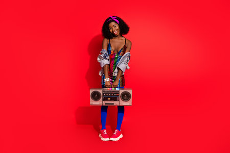Photo of impressed charming curly dark skin woman dressed pinup clothes holding boom box isolated...