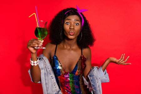 Photo of romantic lady hold cocktail send air kiss wear glossy dress jacket headband isolated red color backgroundの写真素材
