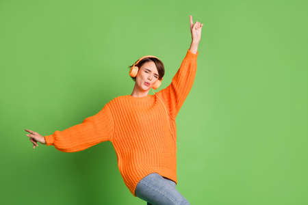 Photo of crazy funny young girl wear headphones good mood dance funky isolated on green color backgroundの写真素材