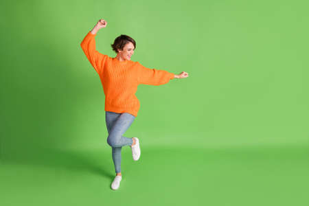Full body photo of attractive crazy funny woman raise hands dance empty space isolated on green...