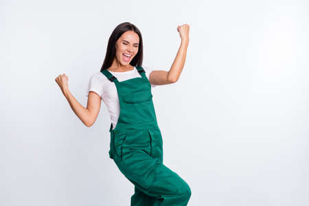 Photo of astonished excited lady celebrate victory close eyes wear green overall isolated white color backgroundの写真素材
