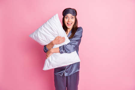 Photo portrait of ecstatic screaming woman hugging pillow isolated on pastel pink colored backgroundの写真素材