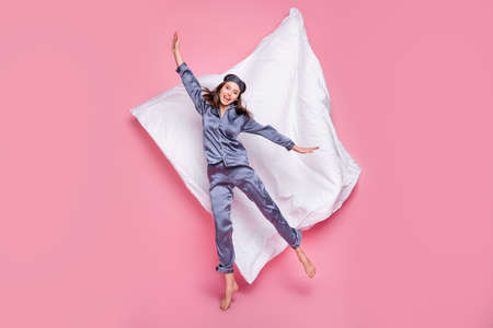Full length photo portrait of excited girl jumping up isolated on pastel pink colored background with blanketの写真素材