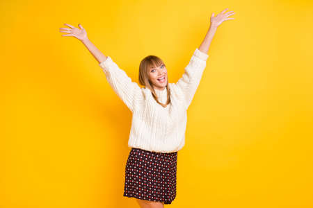 Portrait of satisfied lady raise arms up open mouth wear knitted pullover isolated on yellow color backgroundの写真素材