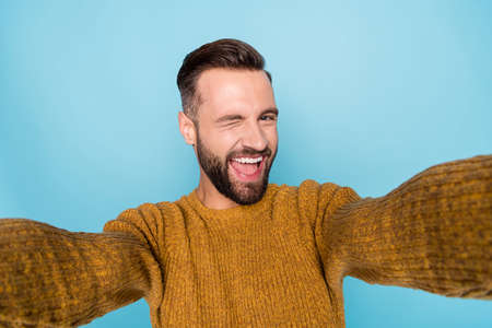 Photo of young happy smiling positive cheerful handsome man take selfie wink eye isolated on blue color backgroundの写真素材