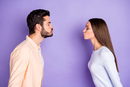 Profile side photo of man and woman air kiss each other boyfriend girlfriend date isolated on violet color backgroundの写真素材