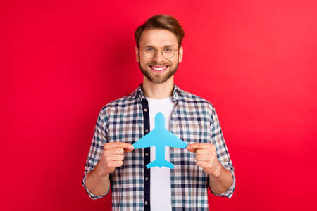 Photo of sweet adorable young guy wear checkered shirt glasses holding paper plane smiling isolated...