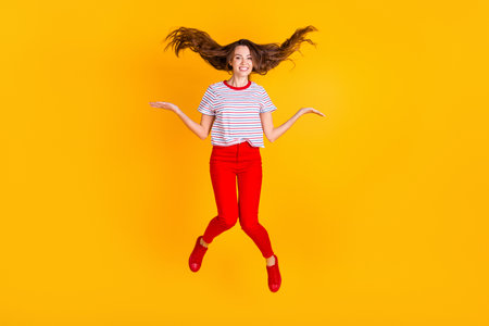 Photo of cheerful lady jump throw hair wear striped shirt red pants shoes isolated yellow color backgroundの写真素材