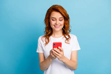 Photo portrait of woman texting holding phone in two hands isolated on pastel blue colored backgroundの写真素材