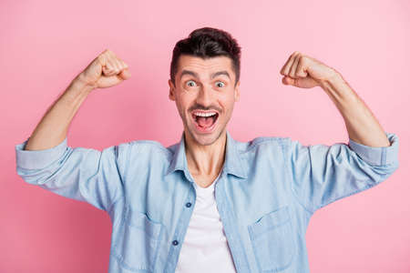 Photo of happy excited strong man raise hands show muscles power isolated on pastel pink color backgroundの写真素材
