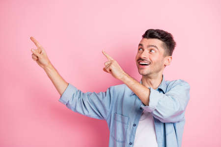 Portrait of nice cheerful guy demonstrating ad copy empty blank space offer rate isolated over pink pastel color backgroundの写真素材