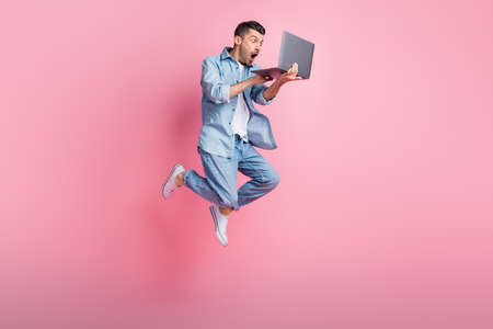 Full length body size photo of jumping programmer amazed working on laptop isolated on pastel pink...