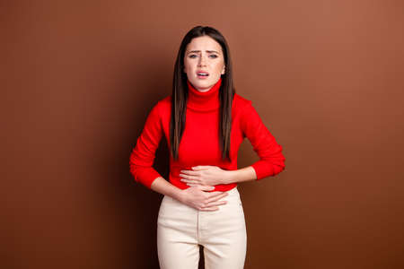 Portrait of pretty unsatisfied lady hands on stomach feeling bad look camera isolated on brown color...