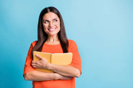Portrait of attractive person hugging book look empty space toothy smile isolated on blue color...