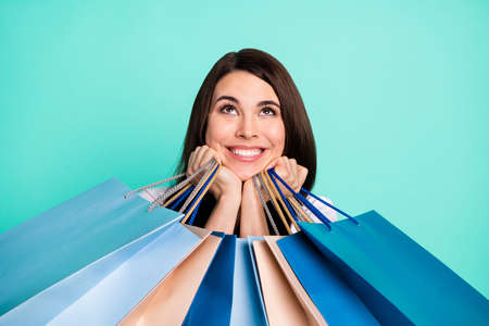 Photo of young girl happy positive smile look empty space hold shopping bags buy consumer isolated over turquoise color backgroundの写真素材