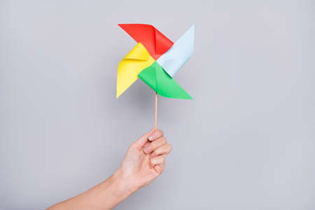 Cropped view of hand holding handicraft carton wind mill isolated over grey pastel color background