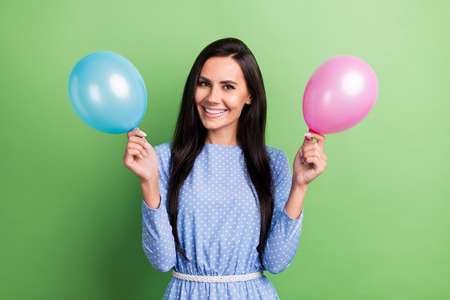 Photo of funny brown hair lady hold balloons wear blue dress isolated on green color backgroundの写真素材