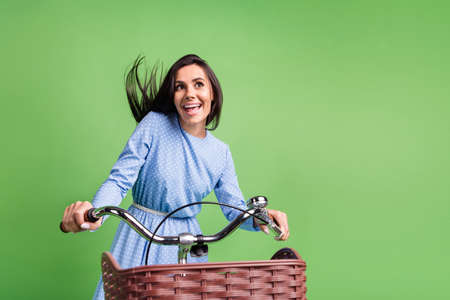 Photo of shiny funny young lady wear dotted clothes smiling driving bicycle looking empty space...