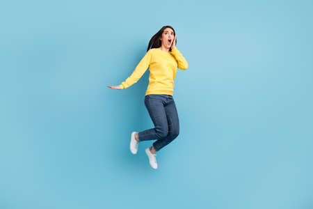 Full size photo of nice stressed brunette long hairdo lady jump wear shirt jeans sneakers isolated on blue color backgroundの写真素材