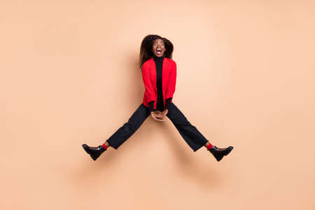 Full size photo of dark skin crazy woman jump up air active travel isolated on pastel beige color...