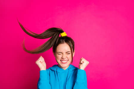 Photo of impressed young girl closed eyes toothy smile fists up won lottery isolated on pink color backgroundの写真素材