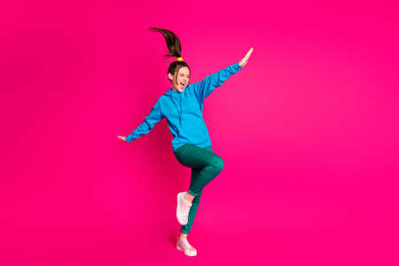 Full length photo of cute sweet lady wear blue sweater dancing standing one leg hands sides isolated bright pink color backgroundの写真素材