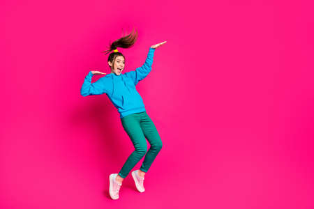 Full size photo of young crazy smiling cheerful girl look copyspace dancing having fun isolated on pink color backgroundの写真素材