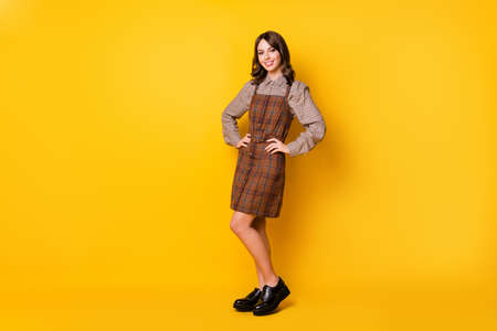 Full size photo of optimistic brunette lady stand wear brown shirt dress boots isolated on vivid yellow color backgroundの写真素材