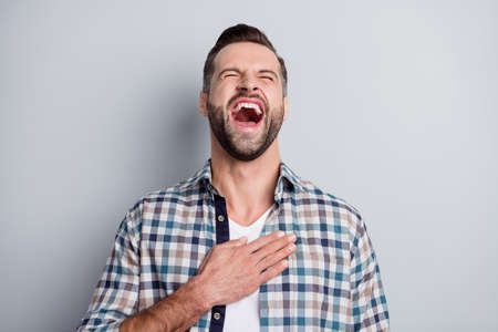 Photo of young handsome attractive happy positive crazy man laughing hold hand on chest isolated on grey color backgroundの写真素材