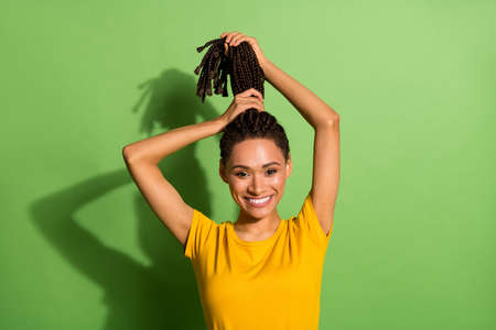 Photo of charming sweet dark skin lady dressed yellow t-shirt hands arms hair tail isolated green color backgroundの写真素材