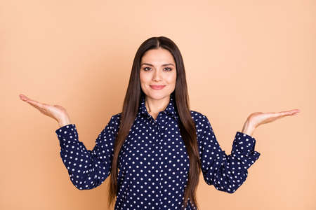 Portrait of pretty lady arms palms hold demonstrating scales proposition isolated on beige color backgroundの写真素材