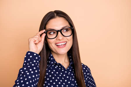 Portrait of charming lady arm touch glasses look empty space toothy smile isolated on beige color backgroundの写真素材