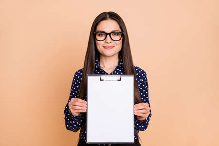 Photo of positive person hands hold demonstrate empty space clipboard list isolated on beige color backgroundの写真素材