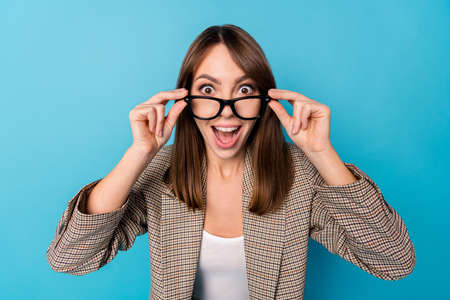 Portrait of brunette impressed lady wear spectacles brown blazer isolated on bright blue color backgroundの写真素材