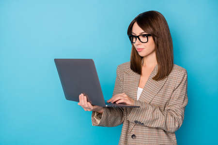 Portrait of nice optimistic brunette lady work laptop wear spectacles blazer isolated on vivid blue color backgroundの写真素材