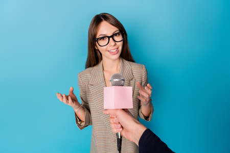 Photo portrait of reporter taking interview from woman holding microphone isolated on vivid blue colored backgroundの写真素材