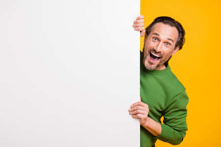 Photo of excited man open mouth white wall empty space wear green pullover isolated yellow color backgroundの写真素材