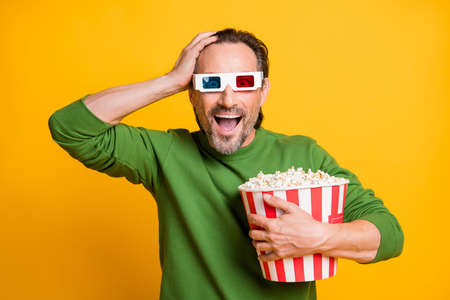 Photo of guy hold bucket popcorn open mouth palm head wear 3d glasses green sweater isolated yellow...