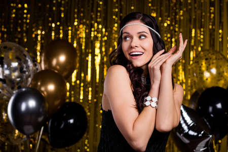 Photo of charming impressed young lady wear glamour dress head band dancing looking empty space isolated glitter backgroundの写真素材