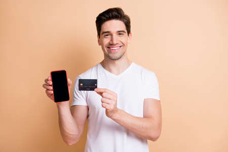 Portrait of cheerful person show empty space display hold debit card good mood isolated on beige...